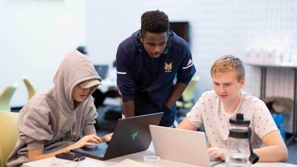 3 male students working together on 2 laptops