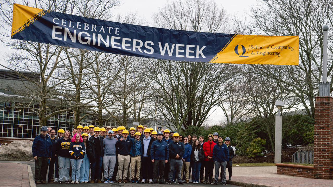 The computing and engineering students stand together underneath a banner on Bobcat Way.