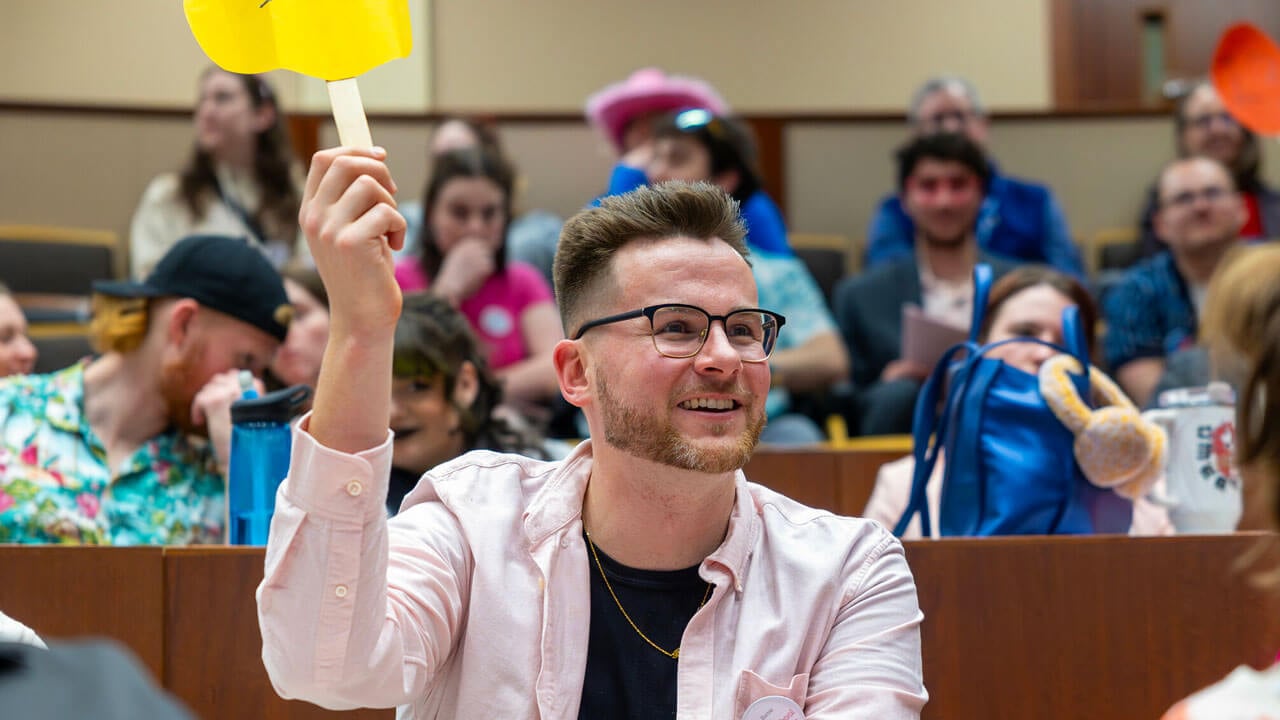 Quinnipiac student holds up his paddle placing a bid for the law auction