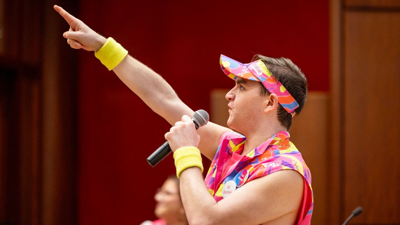 Quinnipiac student dressed up as Ken from the "Barbie" movie points his finger to the audience