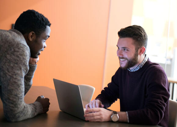 Two dual-degree students talk together in a business classroom