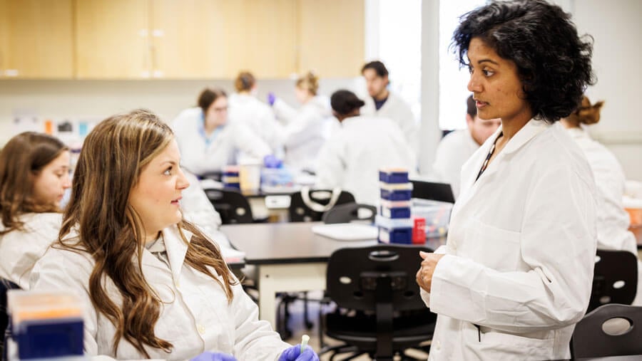 A student discusses with her professor during a lab exercise.