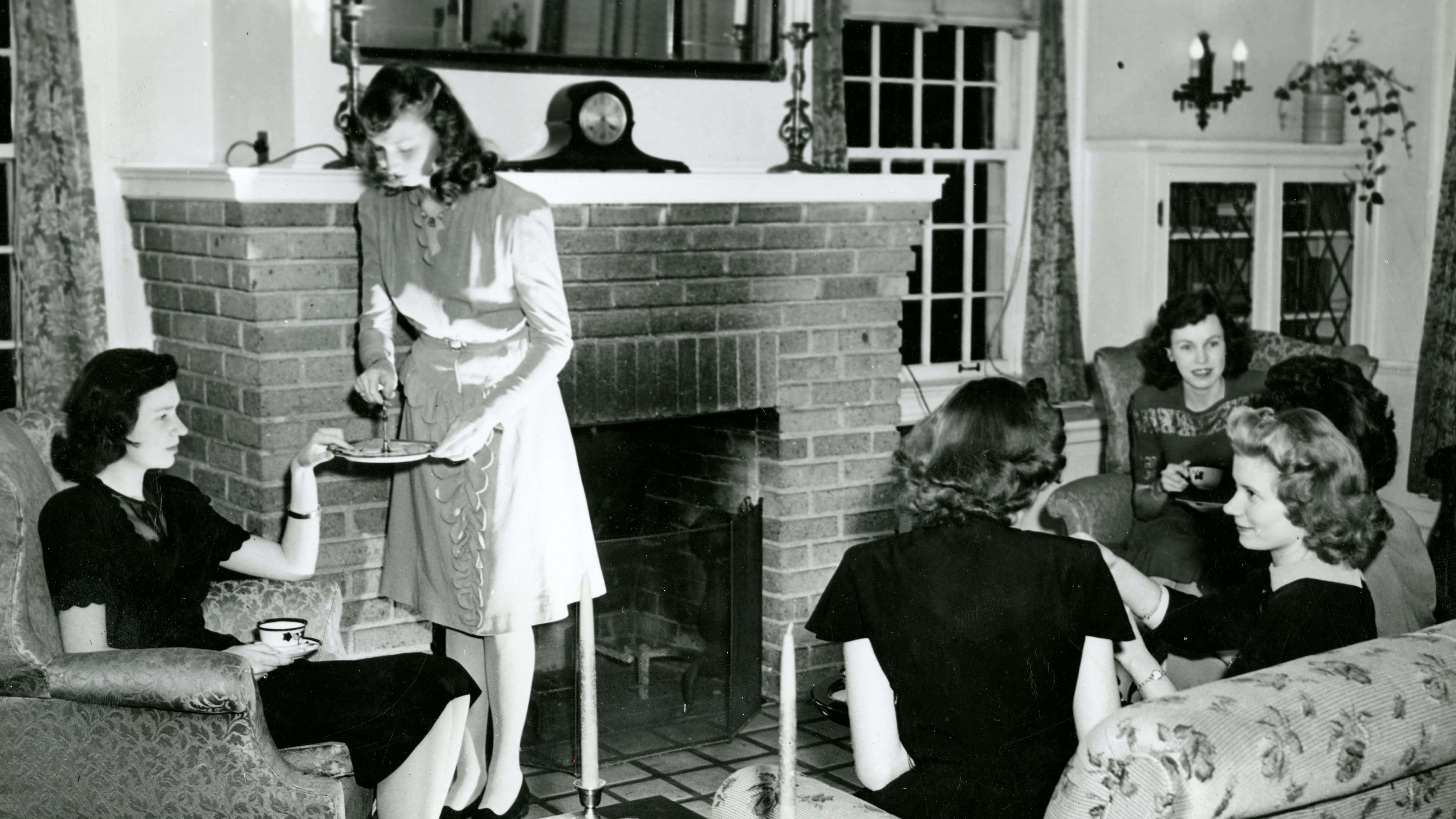 Women gathered by a fireplace while chatting