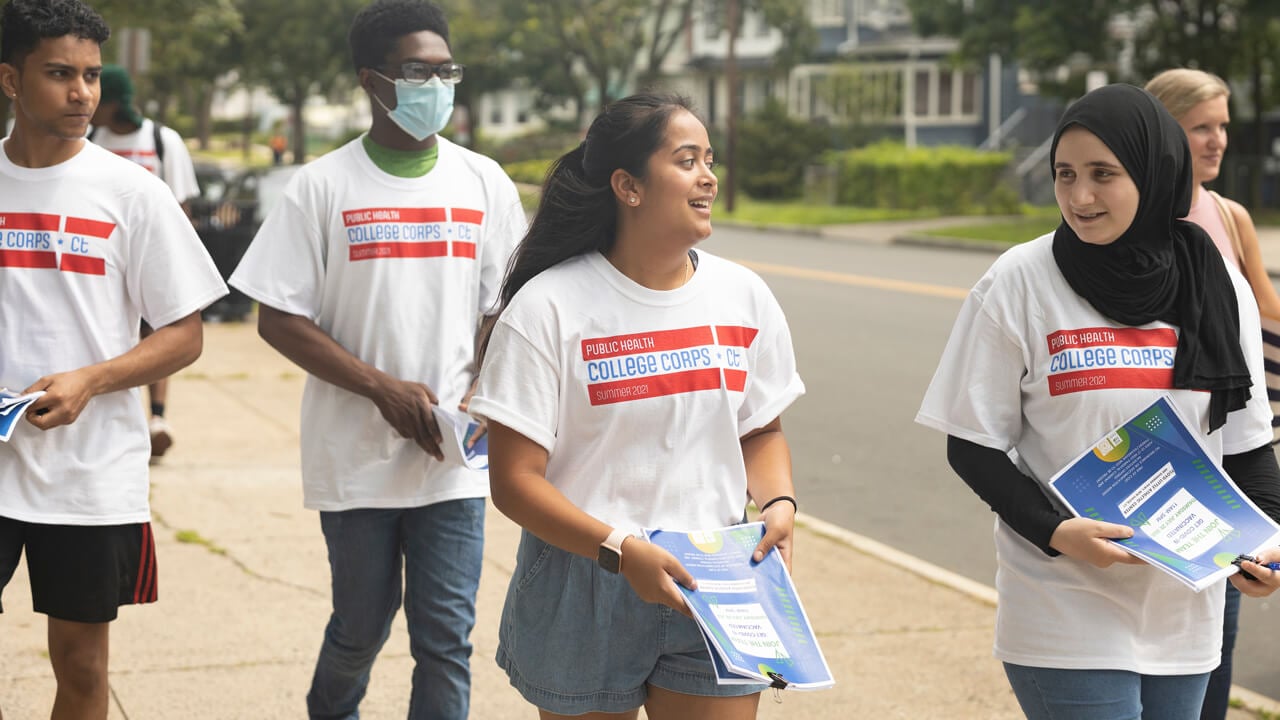 Students walk down the street in a mission to bring COVID vaccine information to community members