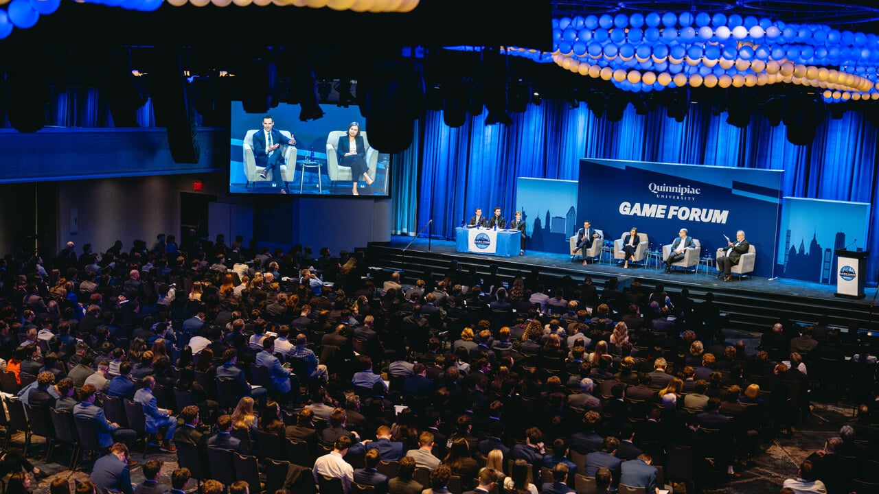 Student leaders and professional panelists sit on the main stage at GAME Forum with a large audience