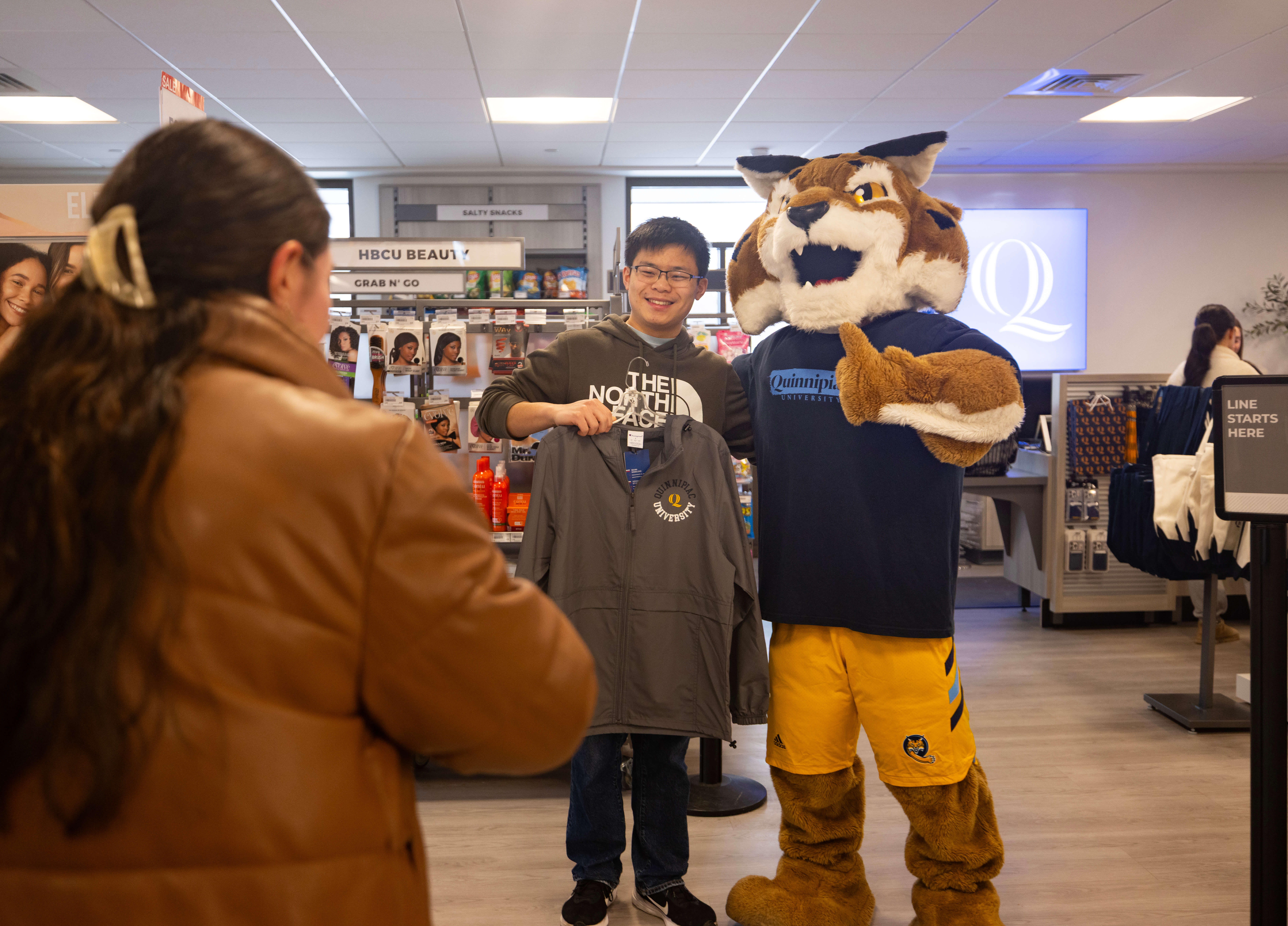 Student poses with Boomer at Quinnipiac's bookstore ribbon cutting