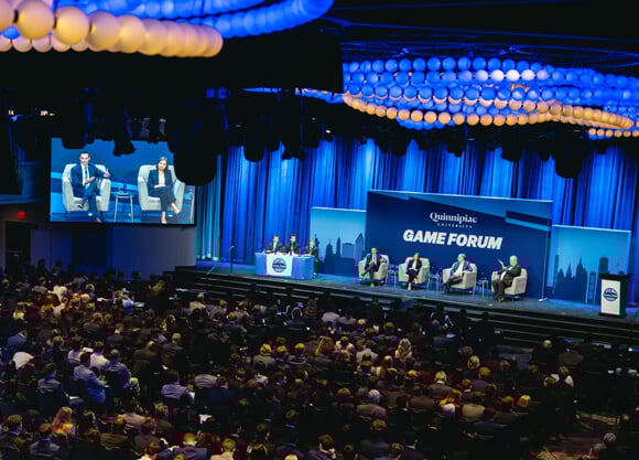 Student leaders and professional panelists sit on the main stage at GAME Forum with a large audience