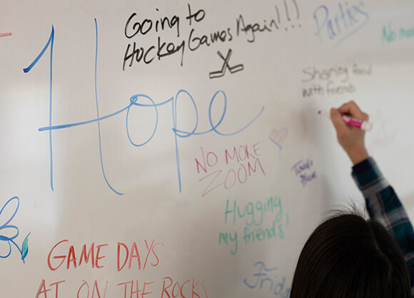 Student writes messages of hope on marker board