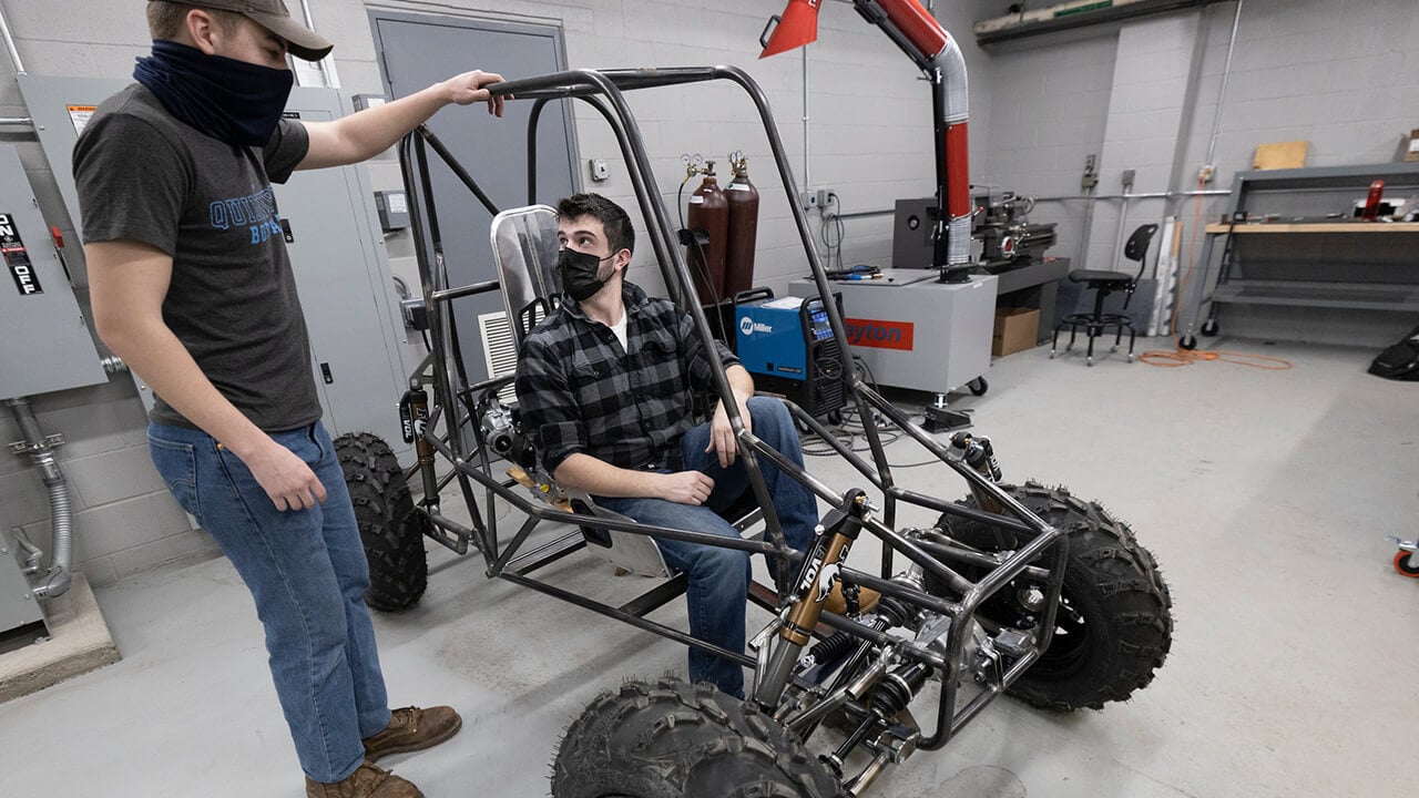 Student sits in frame of car he helped build