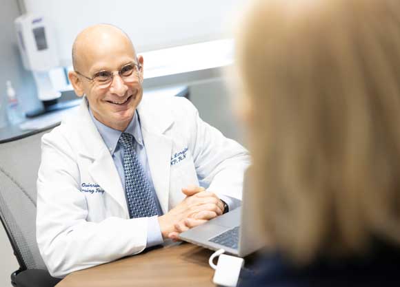 A male NP speaks with a patient at a desk