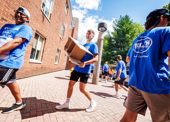 Students assist new students with moving boxes into residence halls