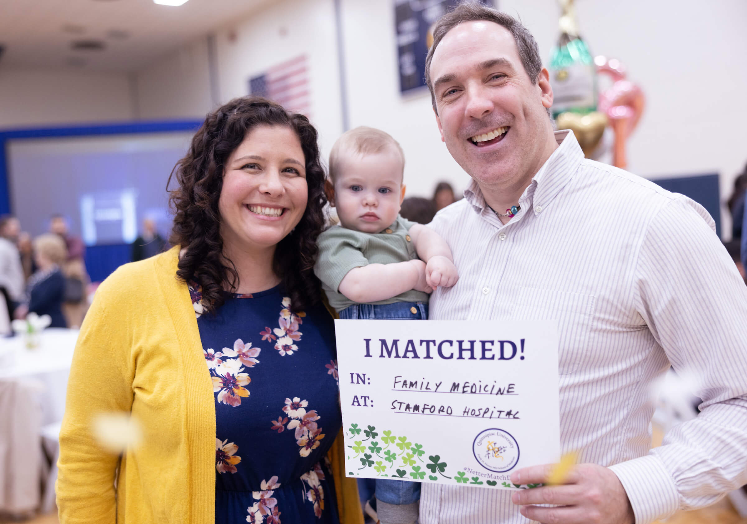 Couple holding baby and match day sign