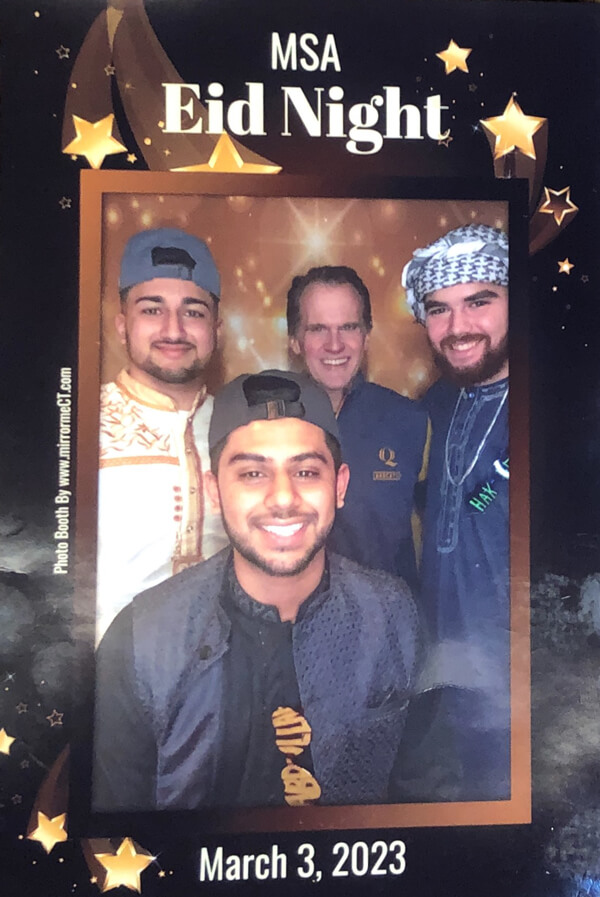 Tom Ellett and students smile in a photo booth during Eid Night