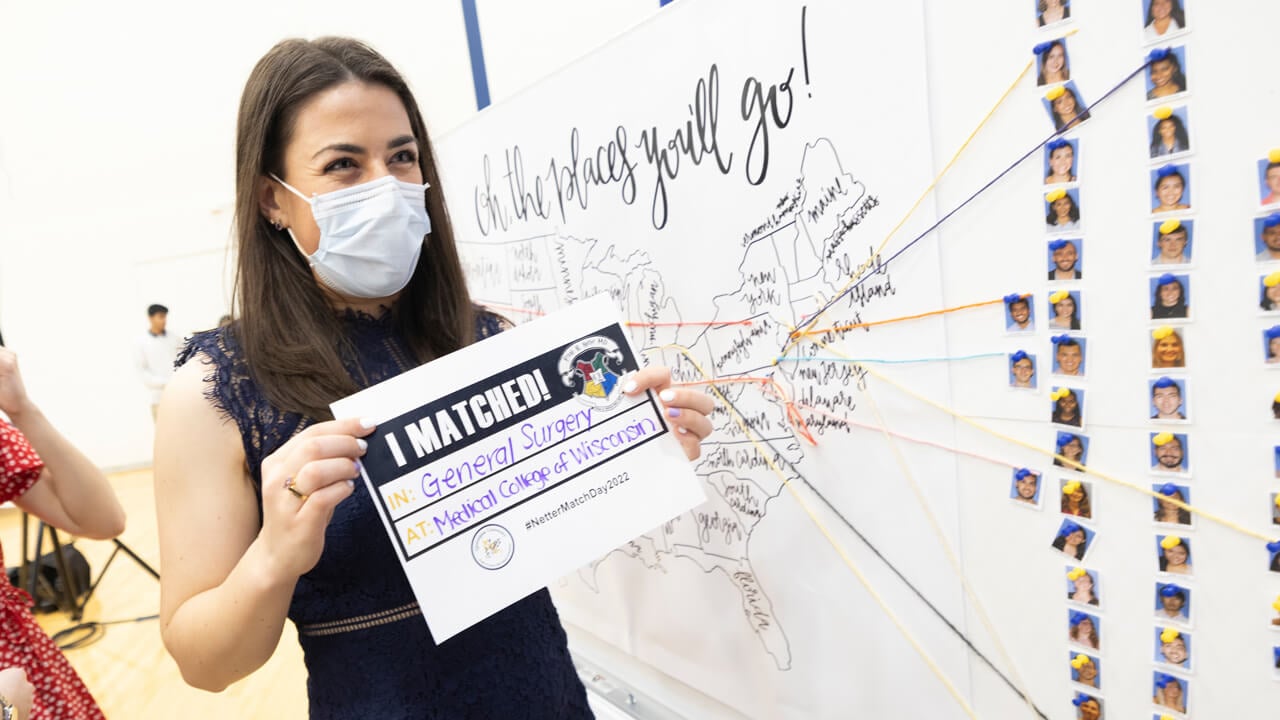 A medical student holds up her match in front of the map of the united states