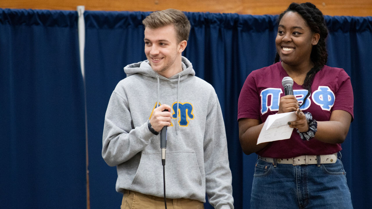 Two students holding microphones during Quinnipiac University’s Greek Week Greek God and Goddess Competition held in Burt Kahn Court on the Mount Carmel Campus on Tuesday, April 2, 2019.