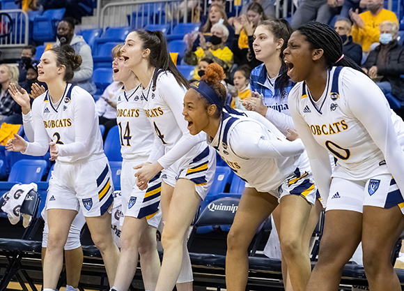 Women's basketball celebrates on the bench.