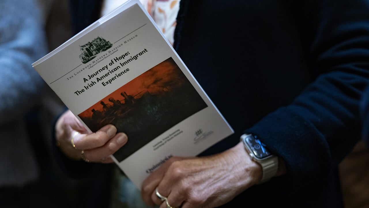 Person holding copy of a book titled "A Journey of Hope: The Irish American Immigrant Experience"