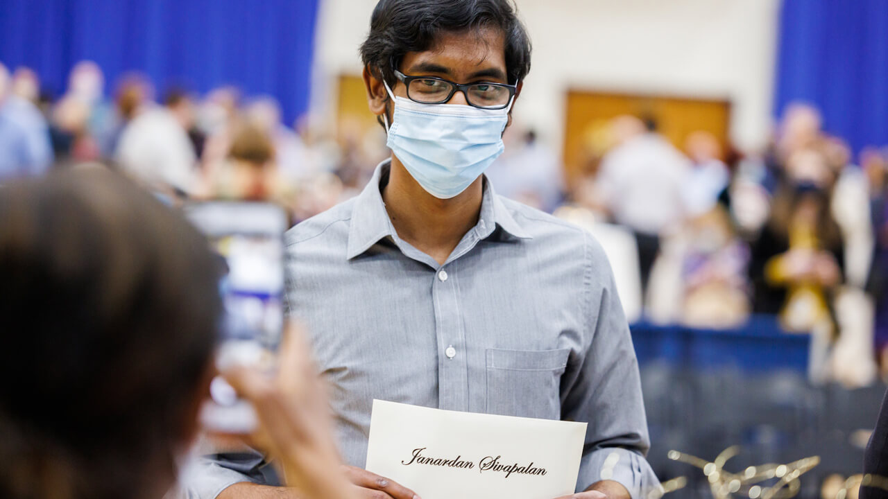 A medical student poses for a photo with his residency match envelope