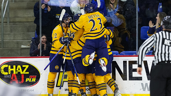 Quinnipiac men's ice hockey players celebrate together on the ice at the M&T Bank Arena.
