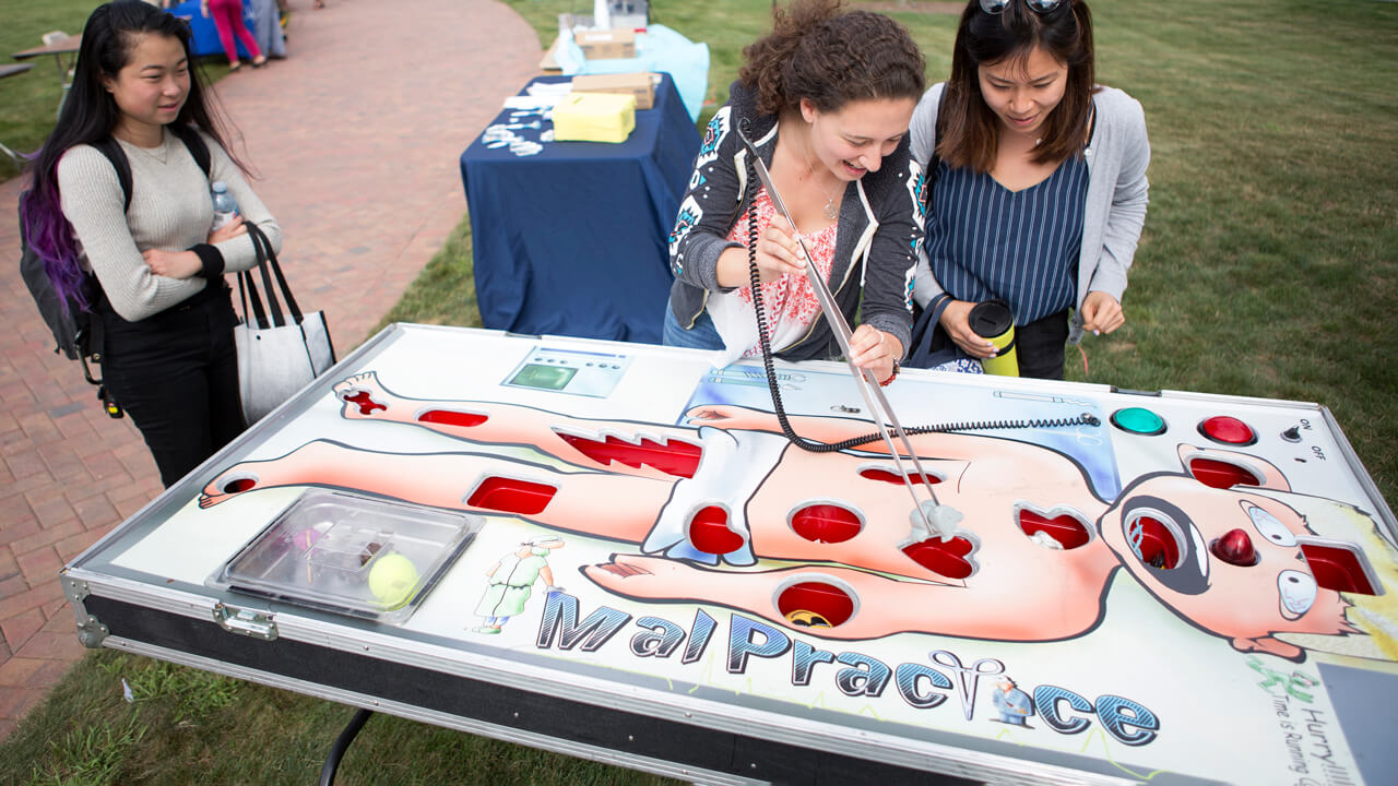 Medicine students playing a life-size version of the game "Operation" on the lawn.