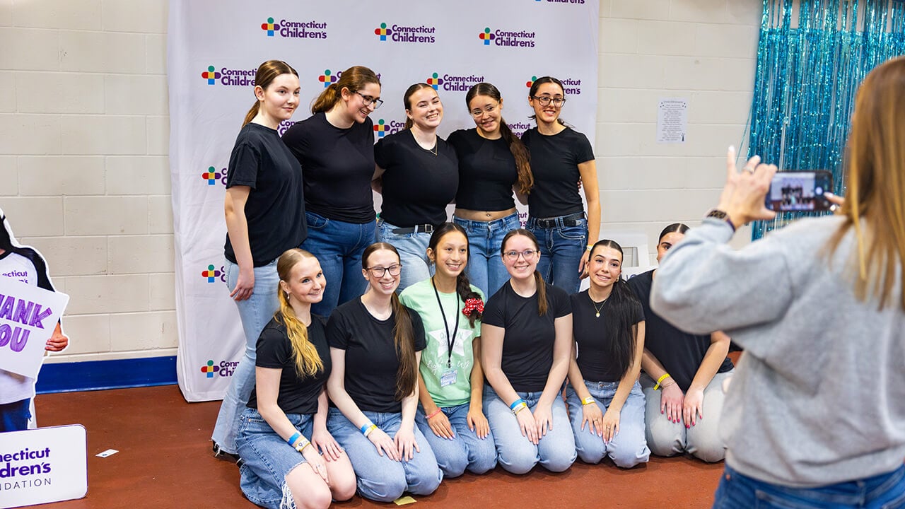 Students stand smiling and posing for a picture with QTHON Miracles