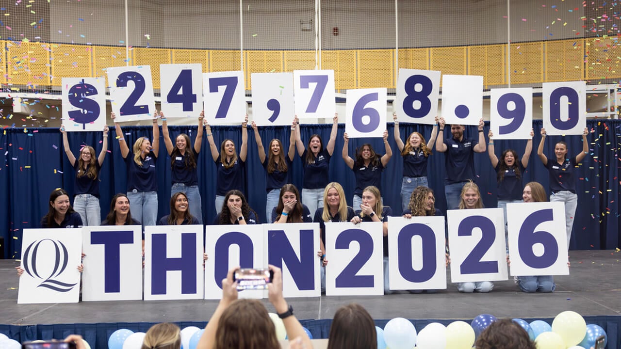 Students hold up sign representing the money raised for QTHON