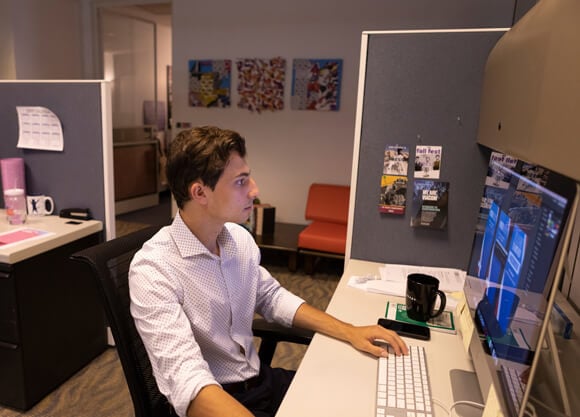 An online student works at a computer at his place of employment