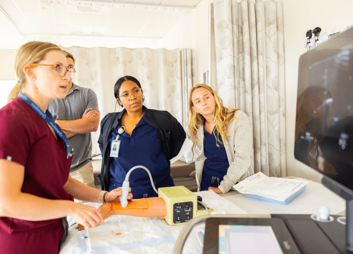 nursing instructor demonstrating a skill to students in a simulation lab