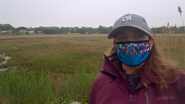 Hillary Haldane wearing mask and standing in an grassy field