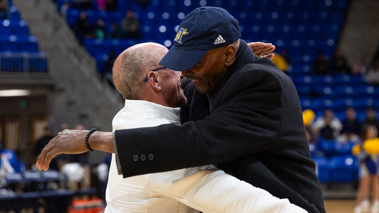 Two men hugging on the basketball court at M&T Bank Arena