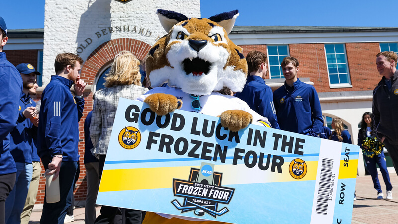 Boomer the Bobcat holds up an oversized Frozen Four ticket