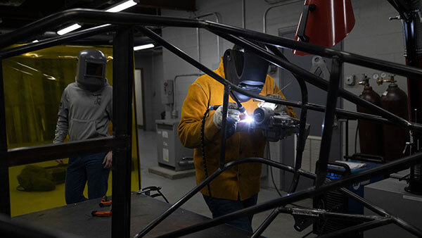 Engineering students weld a car frame