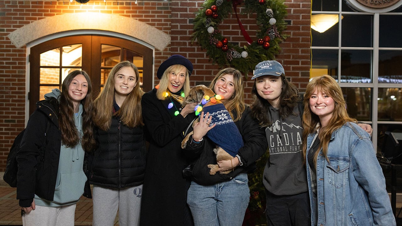 President Hardin in a light-up necklace and her dog pose with students during the Quad Lighting