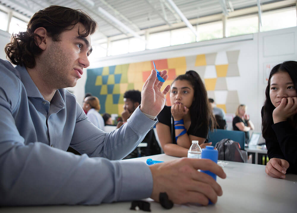A Quinnipiac alumnus works with two local high school students on a team project in the Center for Innovation and Entrepreneurship