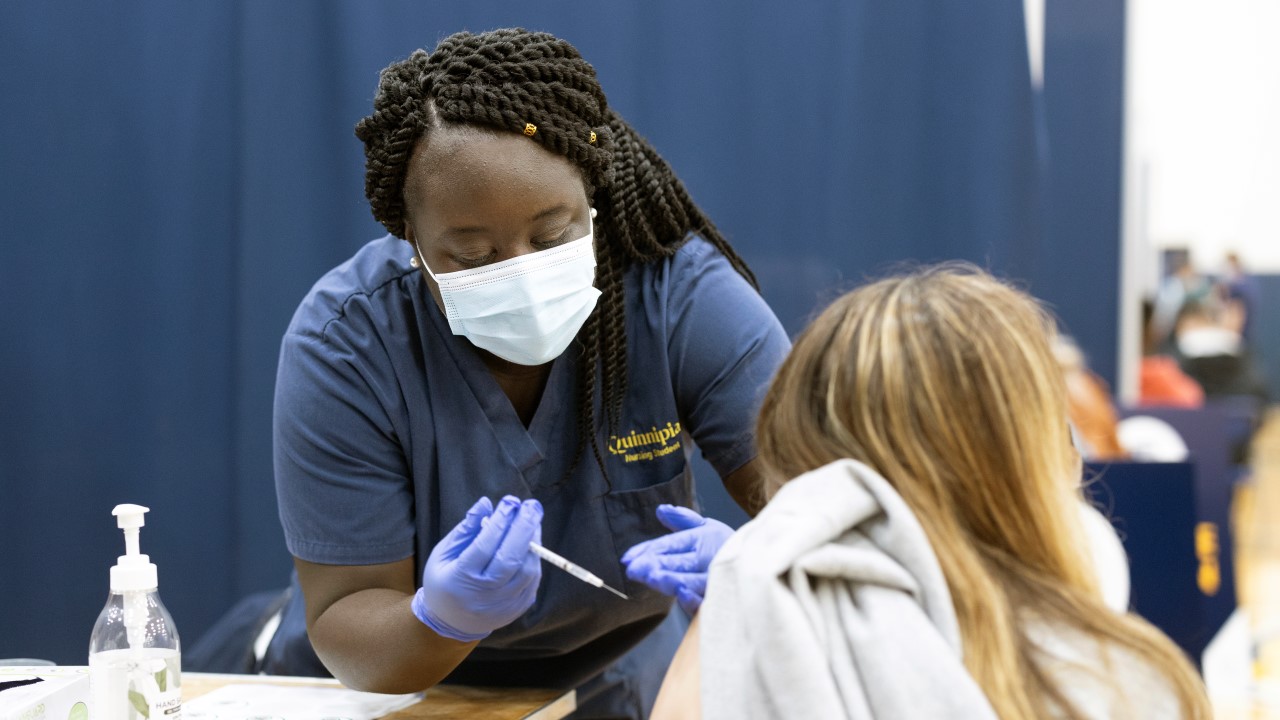 Quinnipiac nursing student Lorinda Asante '21 administers a Covid-19 vaccine to a student patient during a vaccine clinic