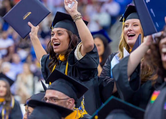 Graduates celebrate with their diplomas at commencement