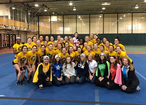 The Acrobatics and Tumbling team and Love Your Melon Super Crew smile with Reese in the recreation center.
