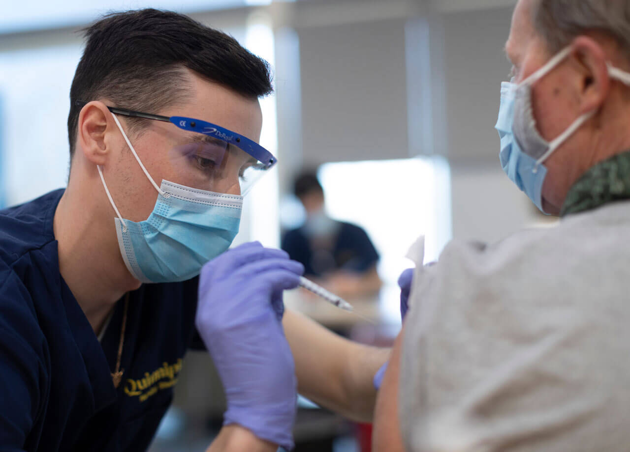 A Quinnipiac student administers a covid vaccine to a patient