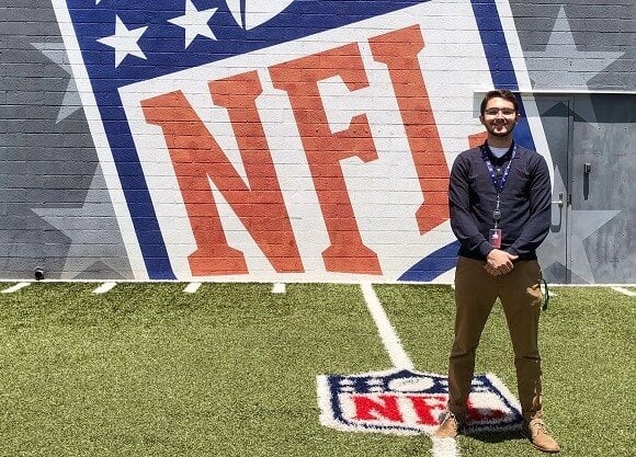 Logan Reardon stands in front of the NFL sign