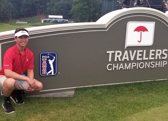 Burnham smiles in front of the Travelers Championship sign