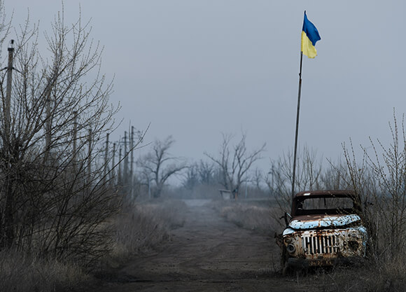 Vehicle in Ukraine with flag in background.