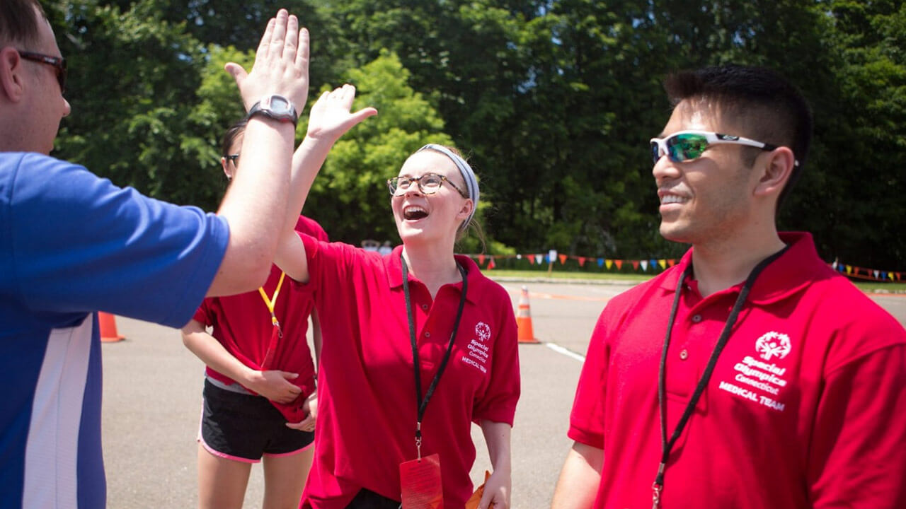 Students hi-five participants at an event at the Special Olympics summer games in New Haven