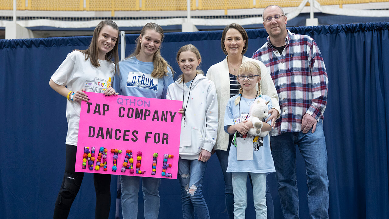 Qu tap company holding sign for QTHON