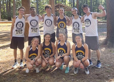 Members of the club running team in their uniforms smile together in Sleeping Giant State Park