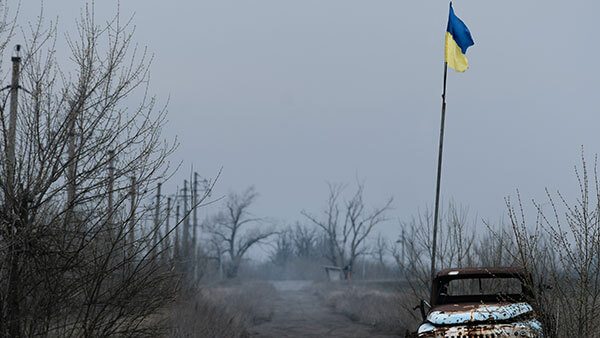 Damaged vehicle with Ukrainian flag flying from it