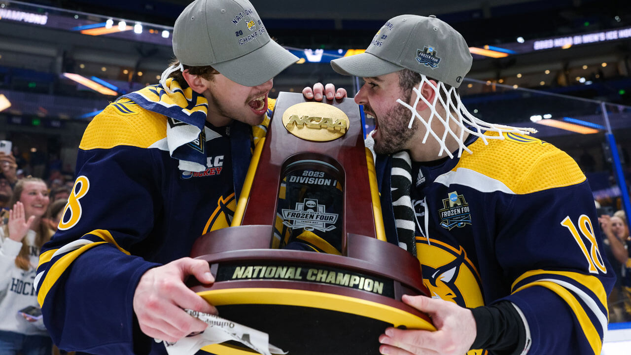 Two teammates cheering while holding trophy