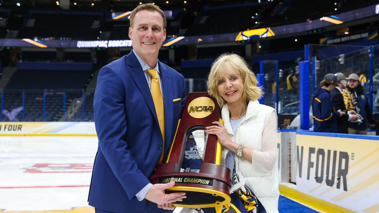 Coach holding trophy with the president of Quinnipiac University