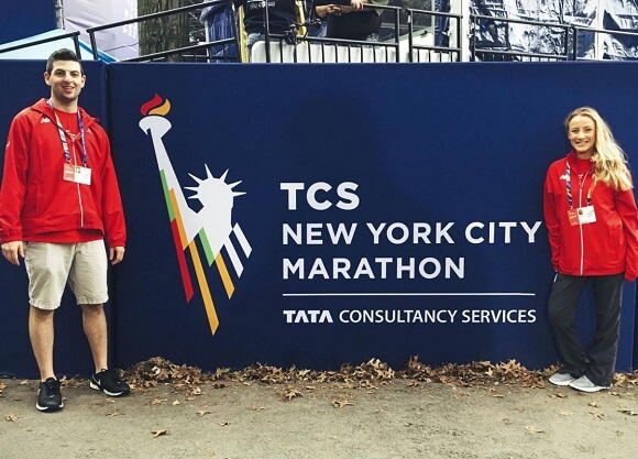 Students pose in front of a New York City Marathon sign on scene at the marathon