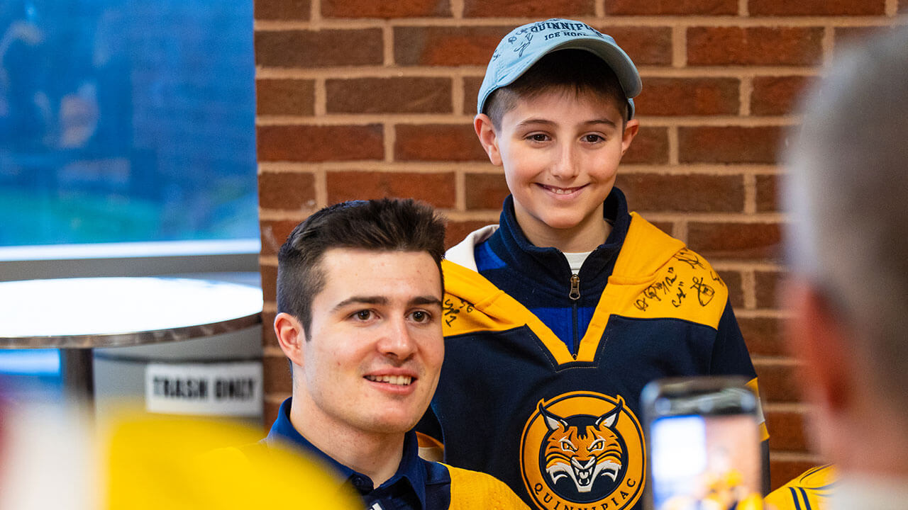 Quinnipiac hockey player poses with a fan