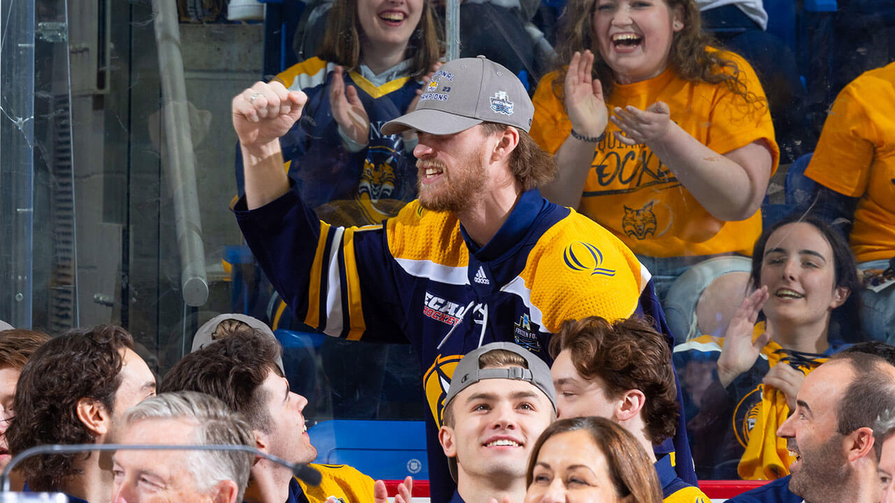 Quinnipiac mens ice hockey player cheers with his teammates and crowd
